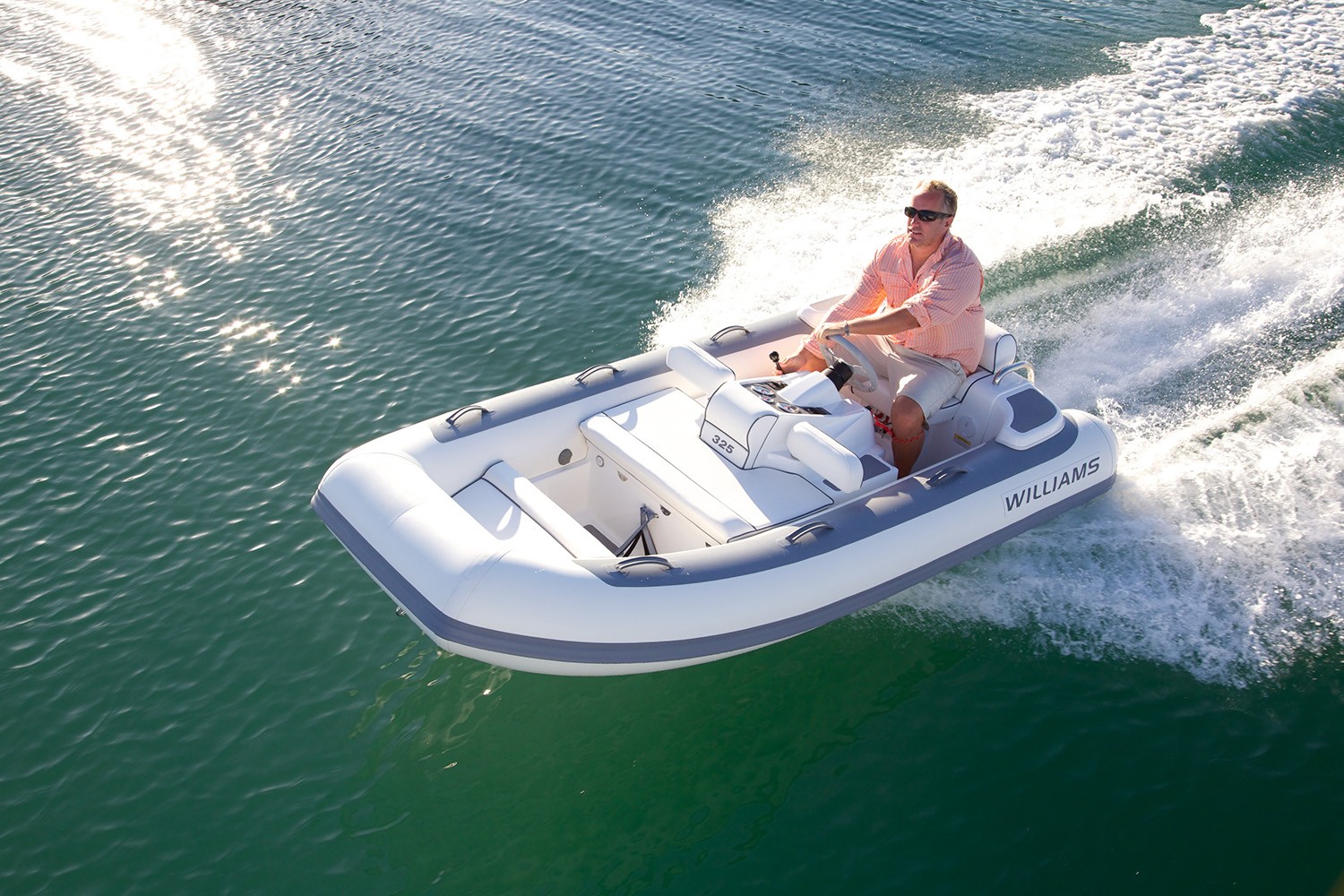 Man cruising a Williams Jet Tender on clear, sparkling water, enjoying a sunny day.